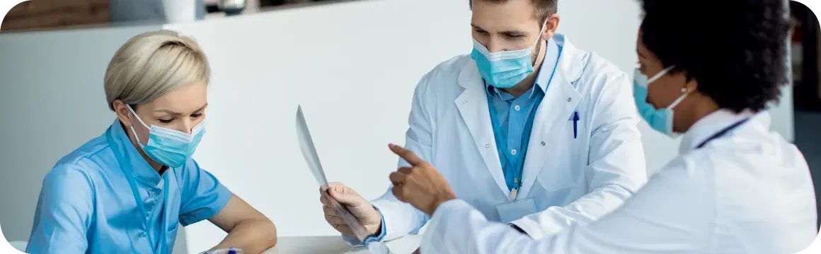 Healthcare professionals reviewing data on a tablet in a clinical setting.